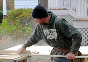 Construction worker sawing wood on a table saw. 