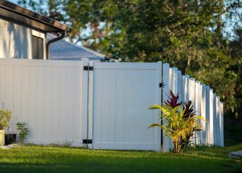 White,Vinyl,Picket,Fence,On,Green,Lawn,Surrounding,Property,Grounds
